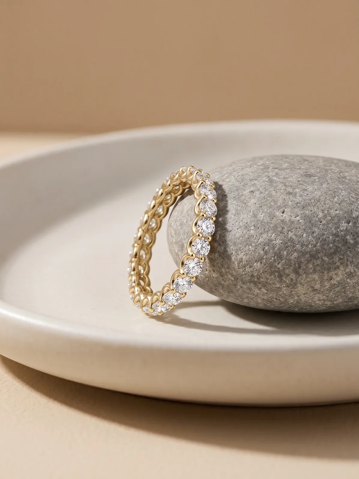 Gold round diamond eternity band leaning on a natural grey stone