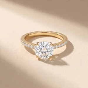 Round brilliant diamond solitaire ring with pavé band in 18K yellow gold