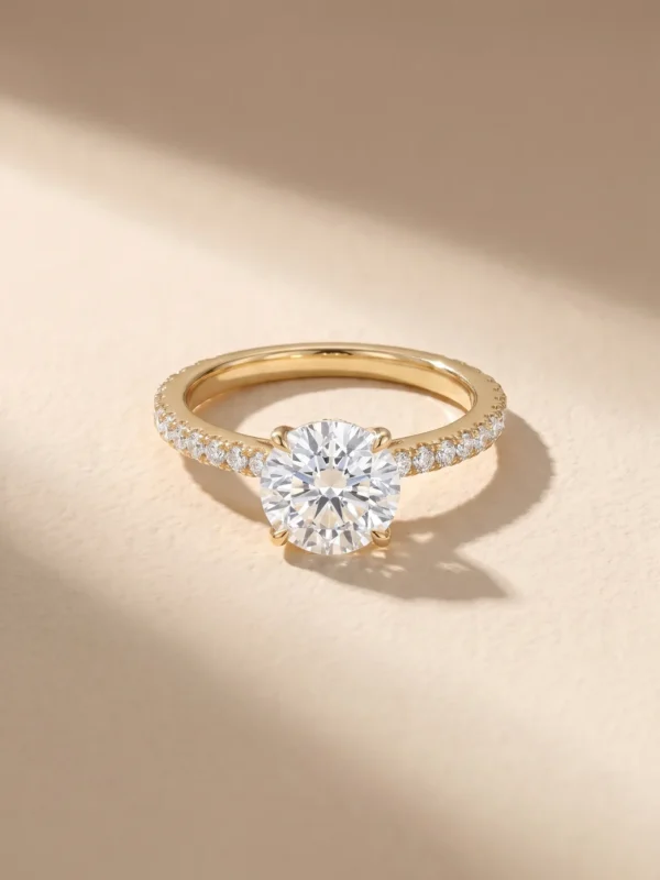 Round brilliant diamond solitaire ring with pavé band in 18K yellow gold
