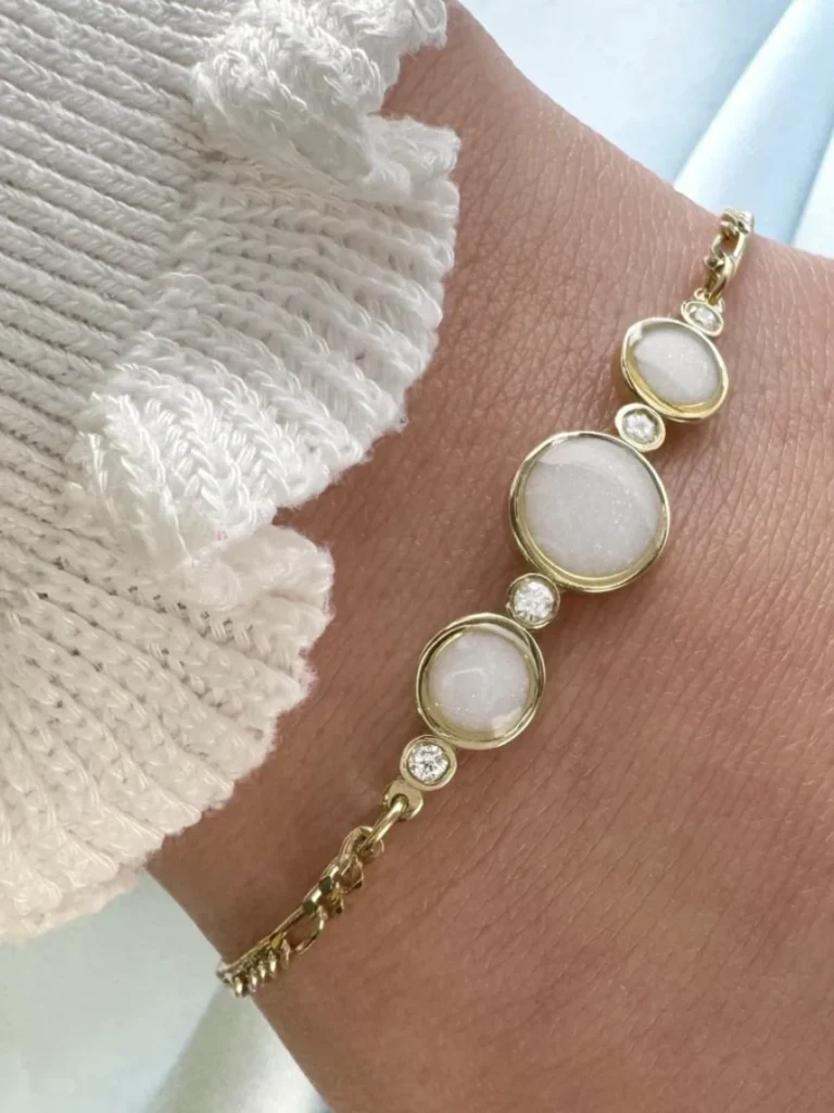 Breast milk keepsake bracelet with three round milk stones in gold bezels and diamond accents, worn on the wrist