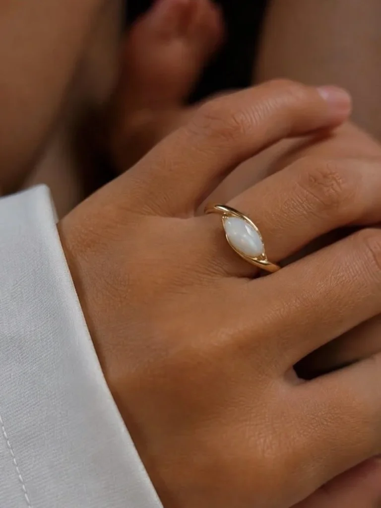 Breast milk keepsake ring with a marquise milk stone in a smooth gold bezel, worn on the hand
