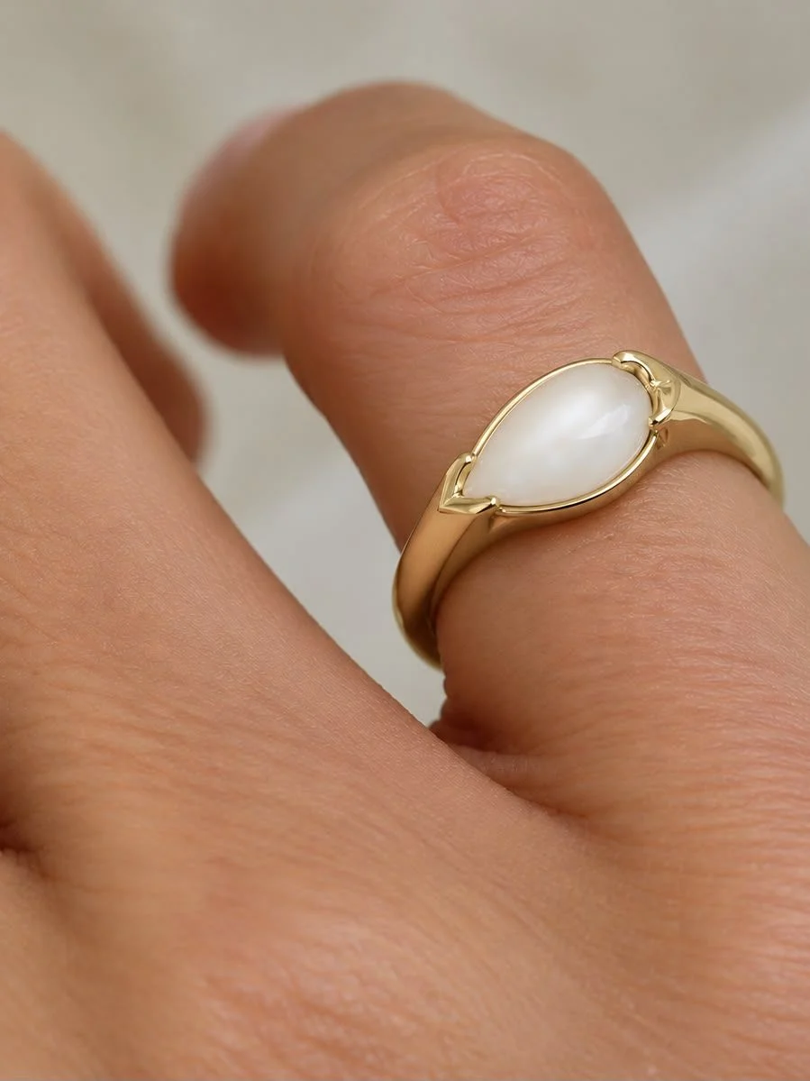 Breast milk keepsake signet ring with a pear-shaped milk stone, worn on the hand