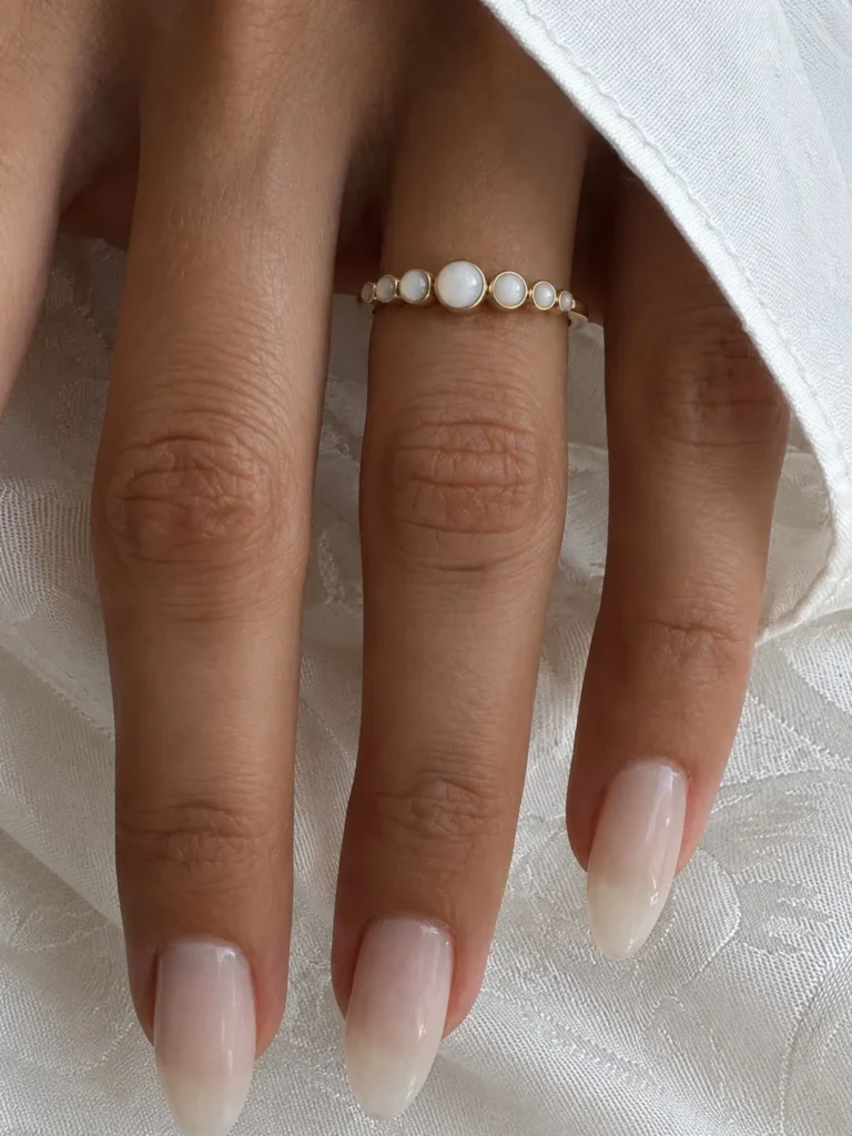 Breast milk keepsake ring with three round milk stones and diamond accents, worn on the hand