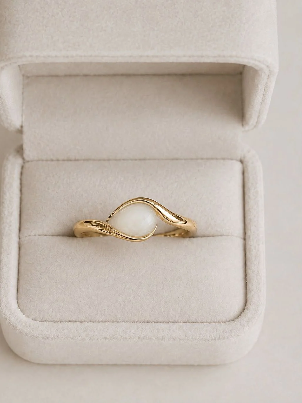 Breast milk keepsake wave ring in gold with a milk stone held between two curving arms, in a jewellery box